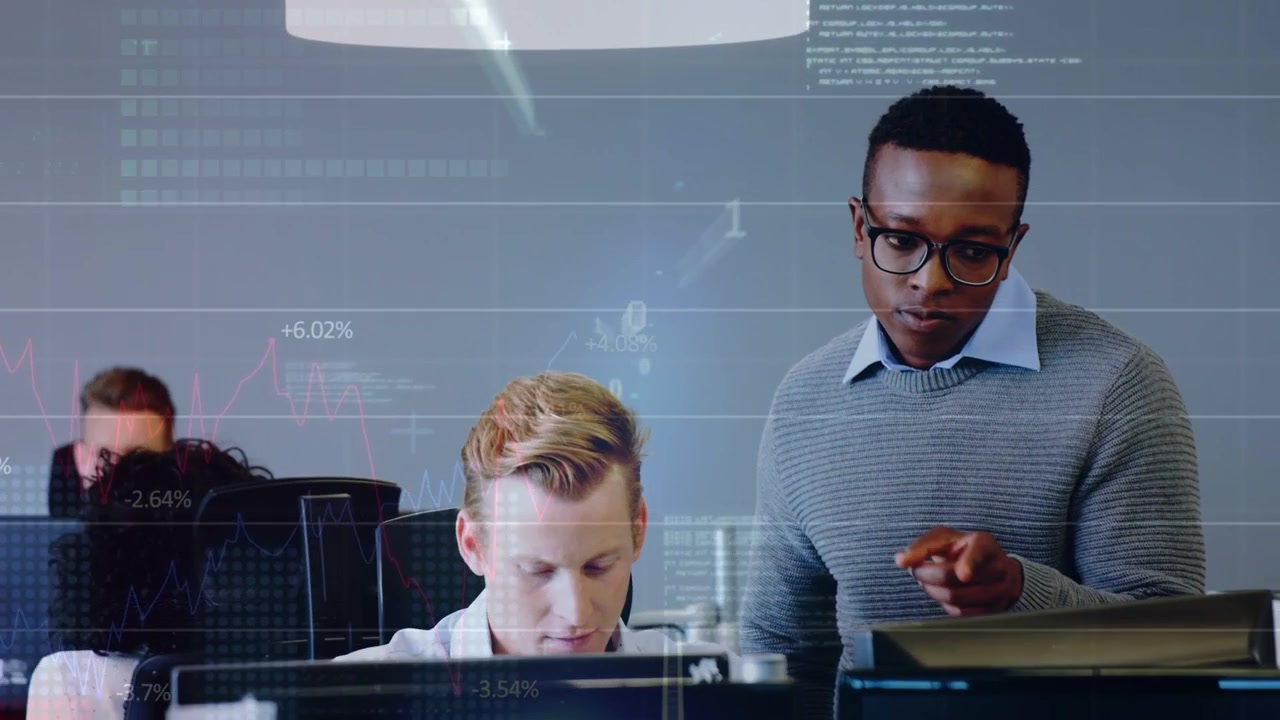 Seated dev typing, standing peer approaching pointing at screens, HUD showing tech charts to review