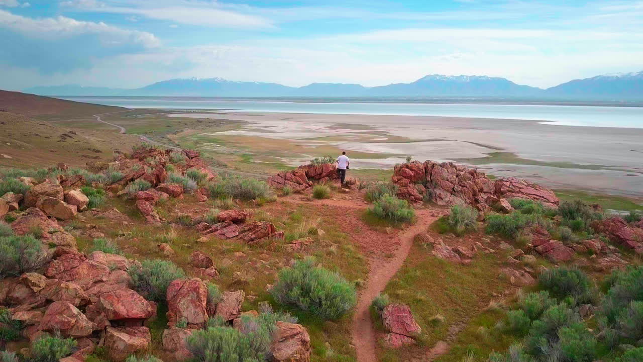 молодой человек смотрит с хребта, на который он только что поднялся, на долину