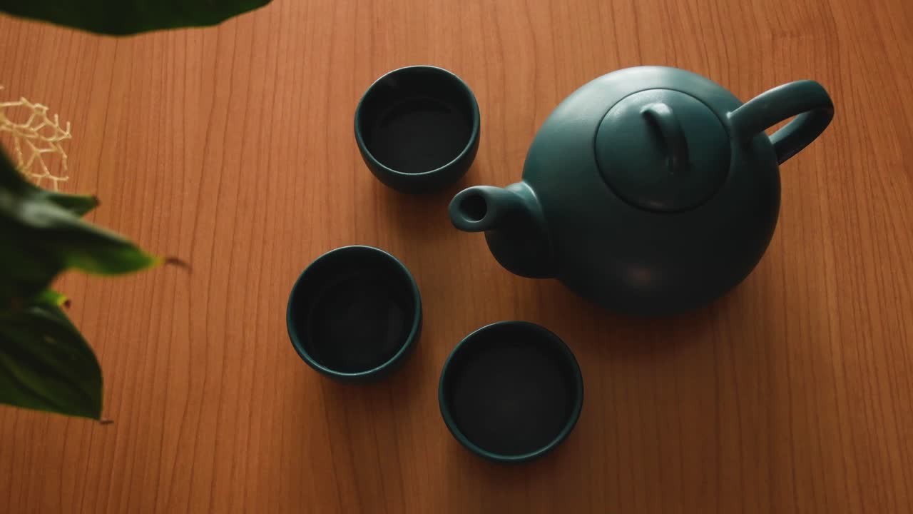 fondo mínimo de un juego de té verde japonés con vapor saliendo de las tazas, sobre una mesa de madera cerca de una planta