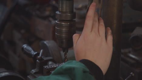 Detail of the drill bit of the bench drill in the workshop with which the mechanic works