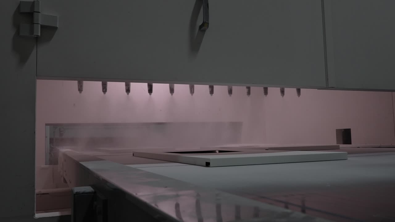 Verniciatura a spruzzo automatizzata di una lastra di metallo all'interno di una macchina industriale per il trattamento delle superfici, focalizzata sull'applicazione uniforme, sulla distribuzione controllata e sulla qualità di rivestimento coerente durante la produzione