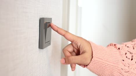 woman's hand turning on a light switch