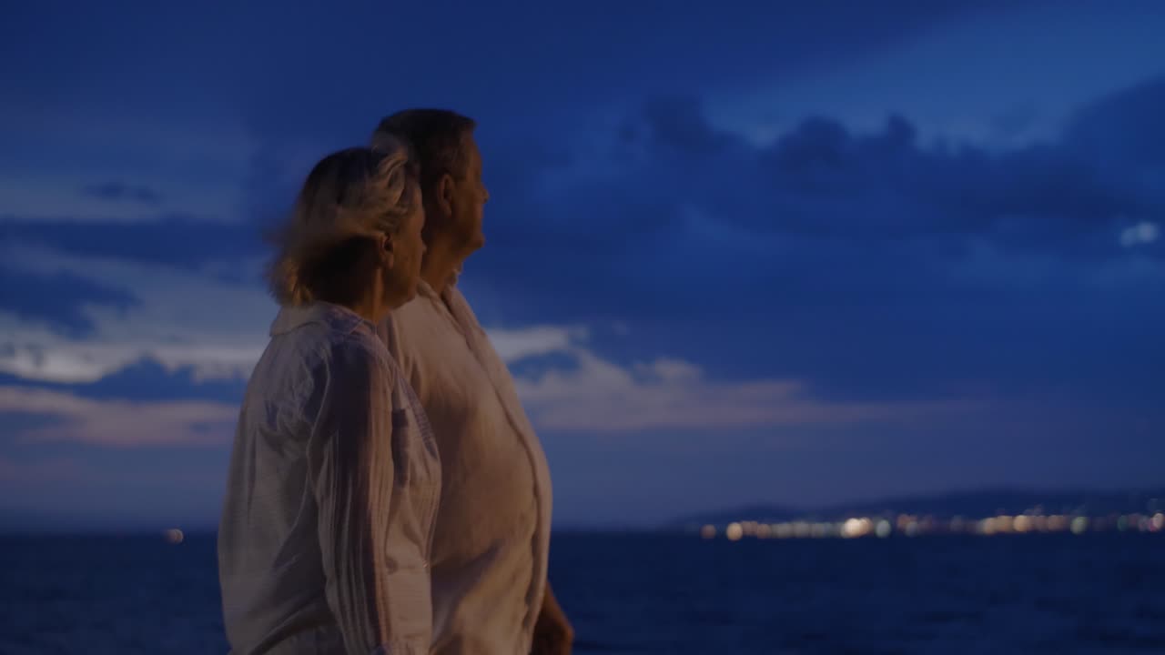 노인 들 이 밤 에 바다 를 따라 산책 하고 있다