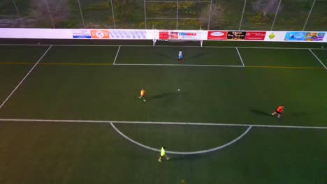 drone shot of people playing football on a field with lights at dusk in santa ponsa, mallorca, spain