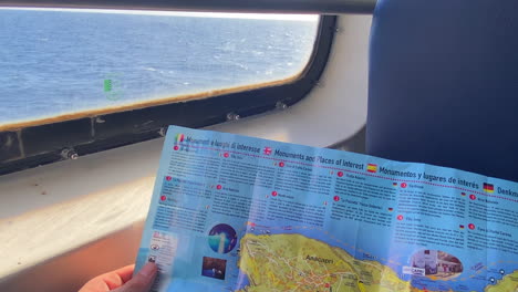 passenger holding a map of capri island inside the traveling ferry