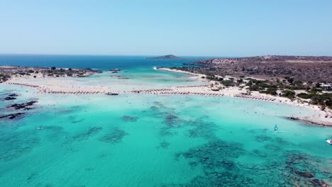 Flyover-Paradise-Island-of-Elafonisi,-wind-surfers-and-boats-at-the-beach