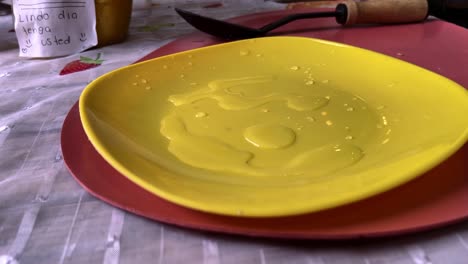 hands reach to pick green tomatoes placed on a vibrant yellow plate, with a knife in the background
