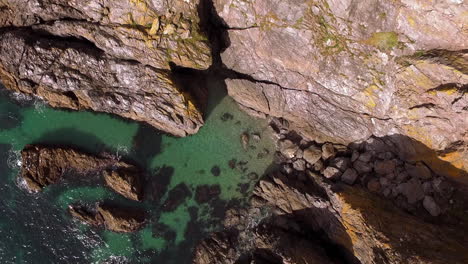 aerial shot looking directly down at the devon coastline while gently rising up to reveal coastal cliffs