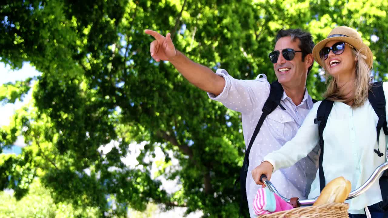 pareja sonriente con una bicicleta en un día soleado