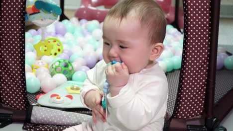 lovely baby girl on her playing area at home with colorful play balls in background