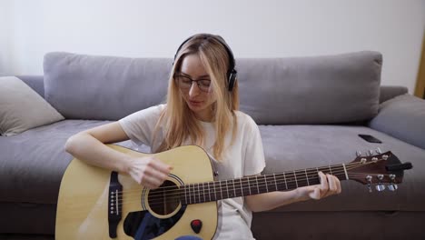 Woman-plays-the-guitar-at-her-home,-happily-having-fun-playing-guitar-and-singing