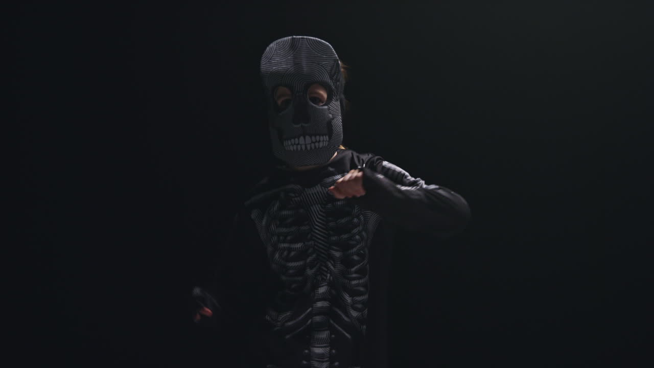 студийный снимок ребенка, одетого в костюм скелета, танцующего на хэллоуин на черном фоне 8