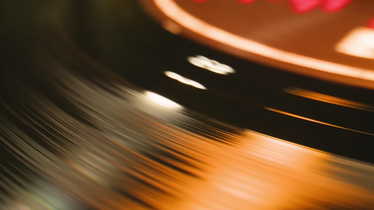 Primo piano di un disco in vinile che gira con riflessi caldi