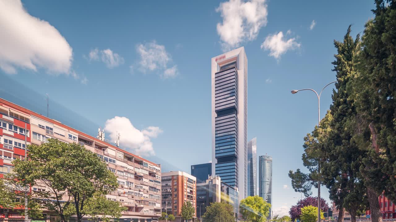 time-lapse de los rascacielos de madrid contra el cielo azul con nubes blancas en una soleada mañana de primavera de negocios y en primer plano de los coches que pasan