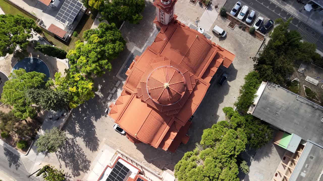A stunning aerial perspective showcases a historic building with a distinctive roof among trees and modern structures in a busy city area during daytime