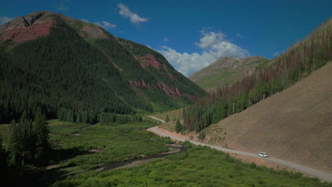 Antena-Dron-Cinemática-Hielo-Lago-Cuenca-Inicio-Del-Sendero-Conduciendo-Furgoneta-Carretera-Del-Condado-Verano-Temprano-En-La-Mañana-Silverton-Telluride-Colorado-Montañas-Rocosas-Bosque-De-álamo-Temblón-14er-Picos-Adelante-Seguir-Desde-Un-Lado-Movimiento