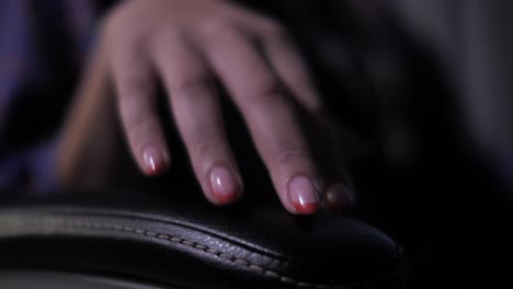 woman tap nervously with manicured fingers against office chair armrest close up