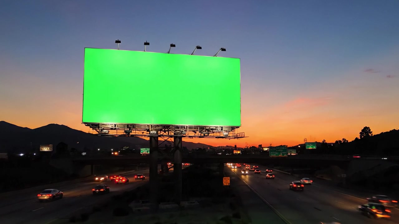 Una cautivadora exhibición de una valla publicitaria verde vibrante contra un cielo crepuscular y nocturno con tráfico en movimiento debajo, enfatizando las oportunidades de publicidad urbana