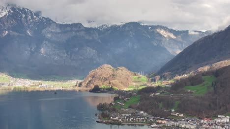 drone shot over the walensee in unterterzen mols in switzerland - lakeshore with houses and high mountains in the background