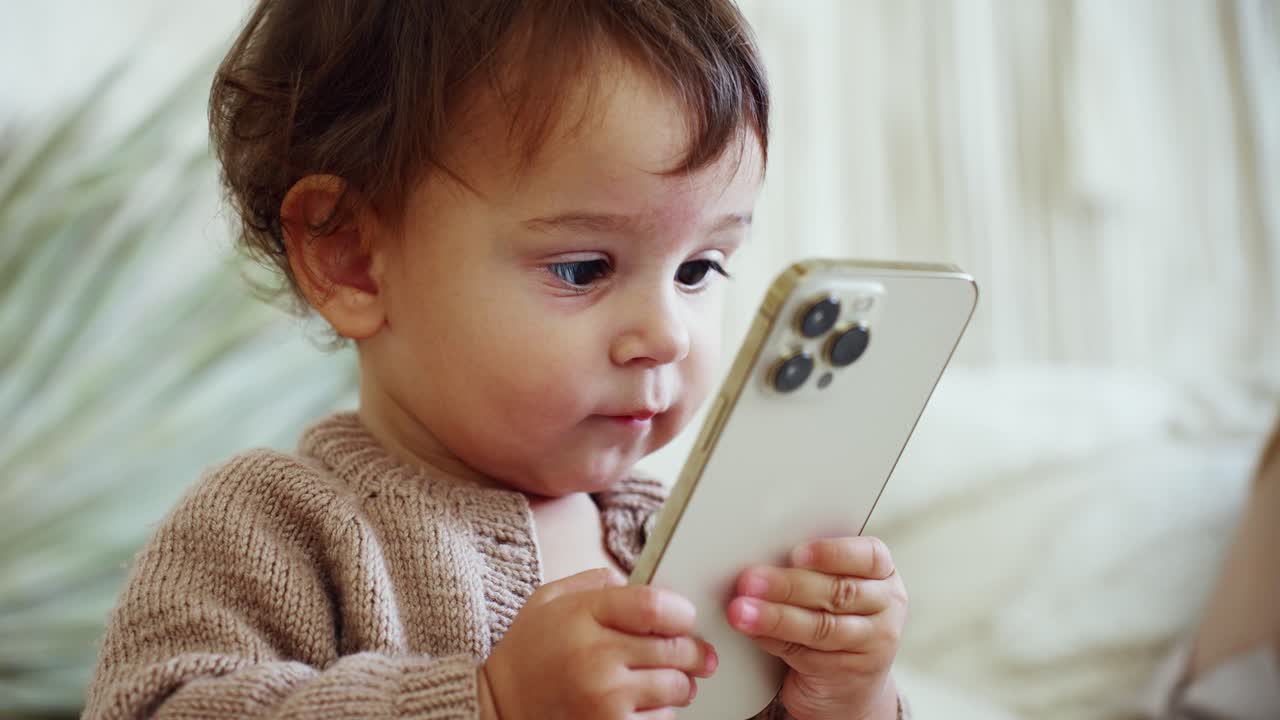 スマートフォンを持って見つめるかわいい赤ちゃん