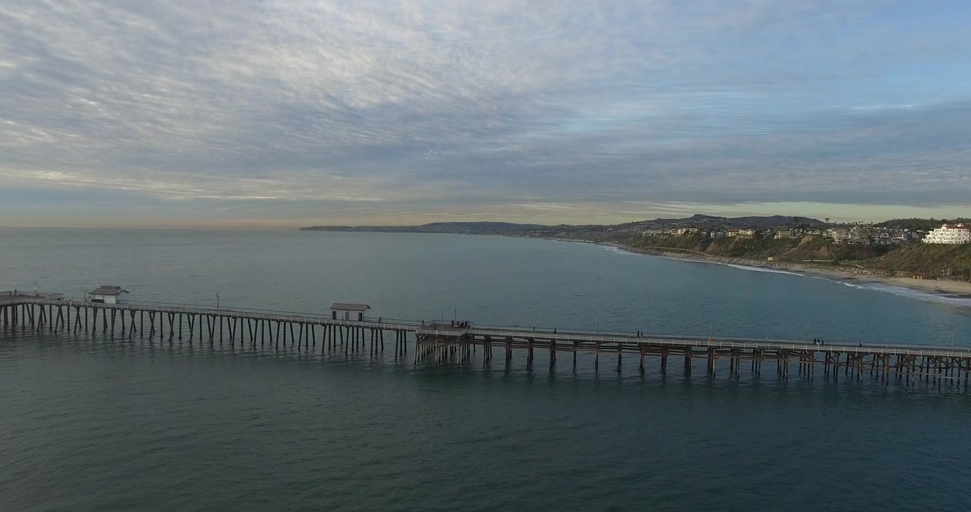 AEREA: Panoramica su un molo sull'oceano sulla costa durante l'ora d'oro.