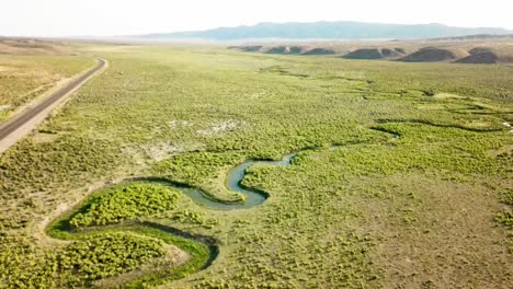 Desert-Highway-at-sunset-and-dusk-with-a-snake-river-and-plateaus-from-a-drone-in-1080p-summer-of-2018