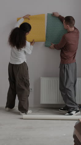 young couple decorating their new home with wallpaper