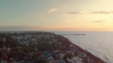 aerial reveal shot of lighthouse surrounded by buildings through the golden-hour shot with a drone in 4k