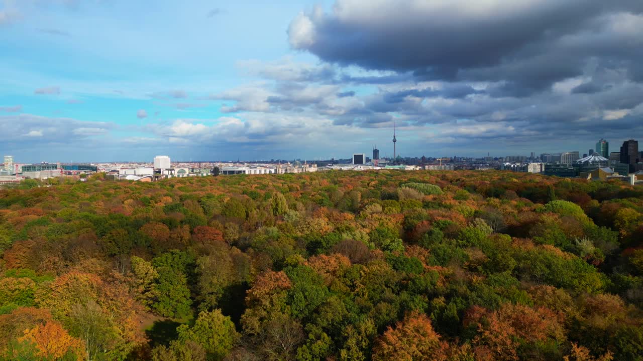 Berlin cityscape with fall colors of Tiergarten Park under cloudy sky. Amazing aerial view flight descending drone