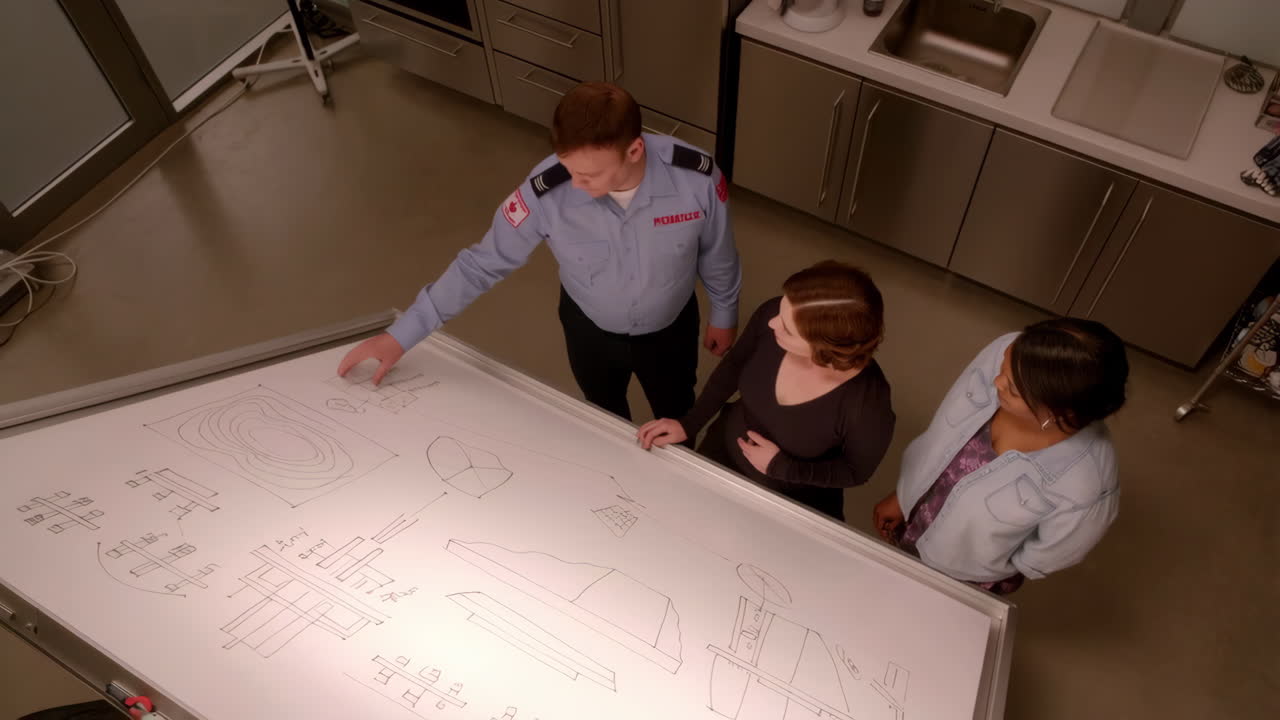 Three people discussing diagrams on a large whiteboard