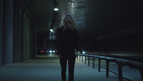 Female-person-night-walk-at-highway-wearing-urban-clothes-in-driving-tunnnel.