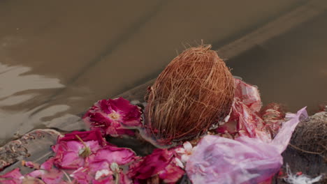cerca de ofrecer flores y coco mezclado con bolsa de plástico flotando en el río