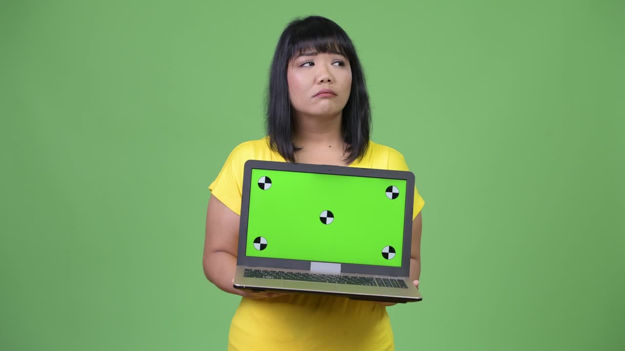Beautiful Asian woman thinking while showing laptop