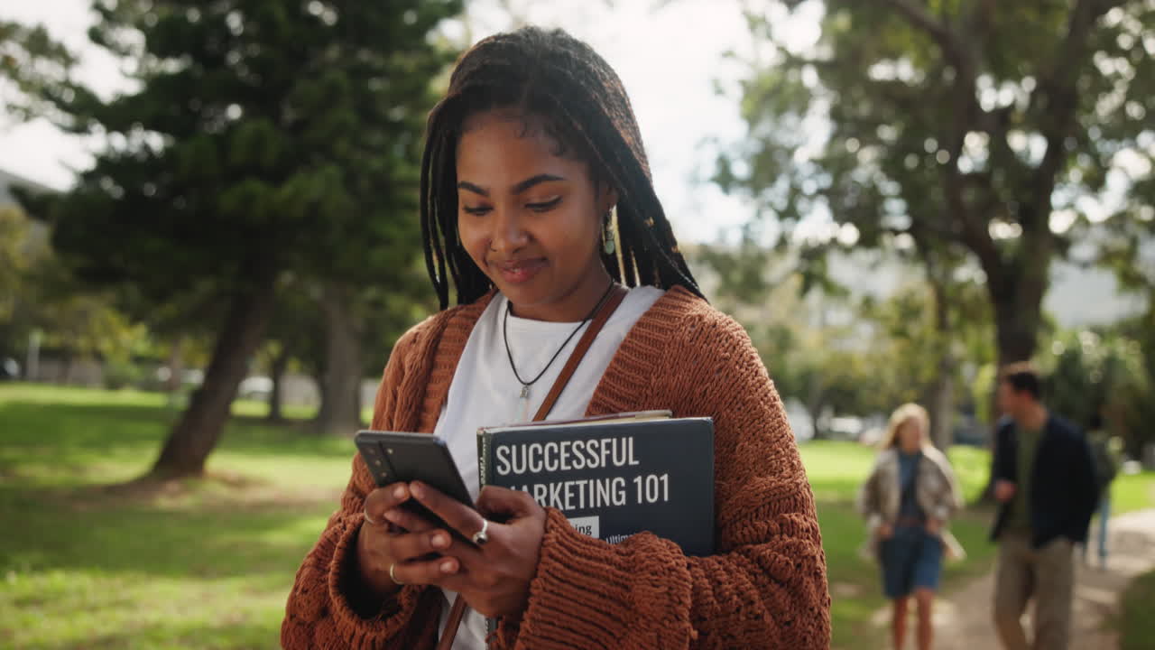 College student texting on phone with book