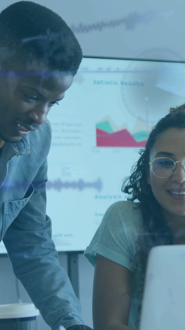 Vertical video: Seated woman watching man point, causing animated charts on display for business