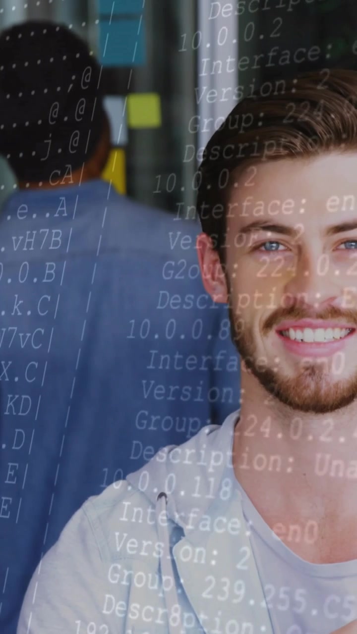 Vertical video: Man at desk holding blue marker, on pullback causing tech code over face for demo