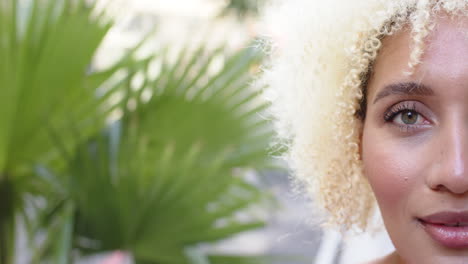 A-young-biracial-woman-with-curly-blonde-hair-smiles-warmly-in-Sydney,-copy-space