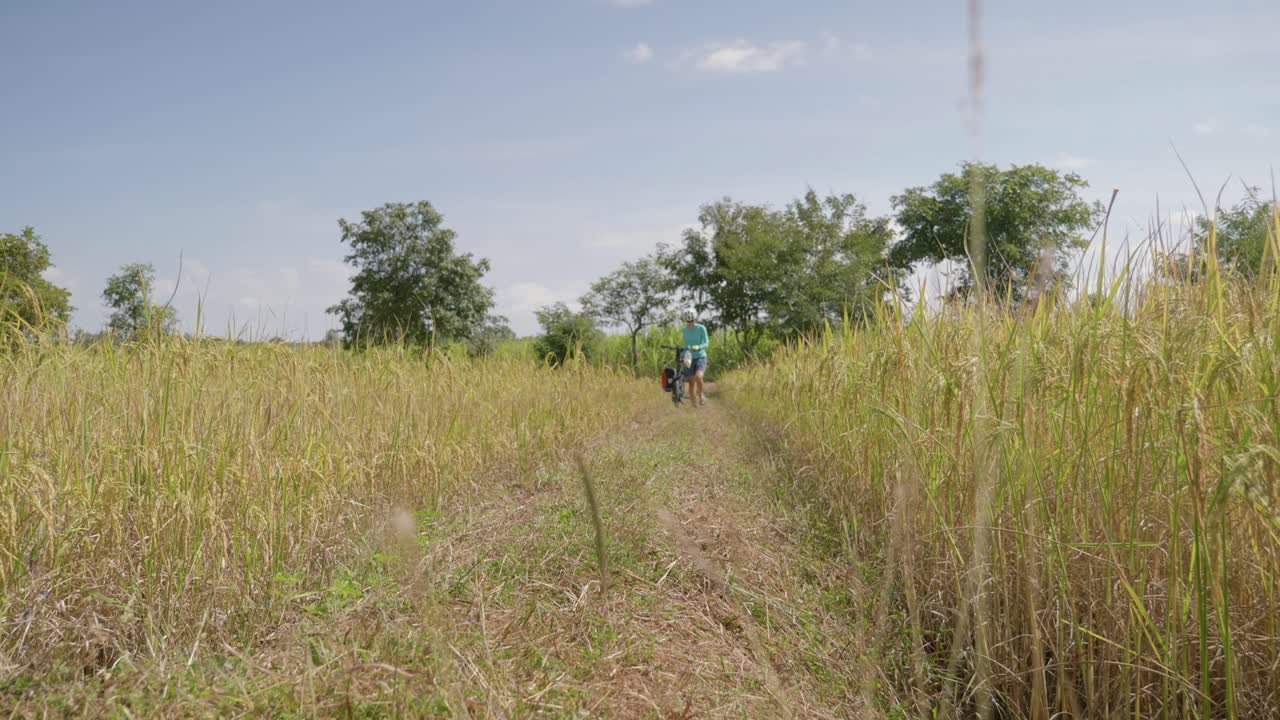 산의 풀밭을 자전거로 걷는 외로운 여성 사이클리스트의 고정 영상