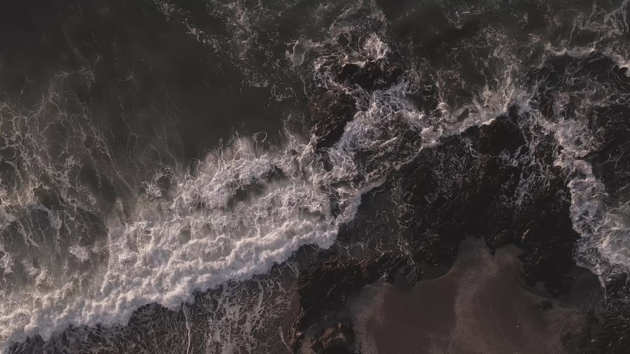 Aerial view birds eye perspective overlooking slow motion foaming ocean waves scene