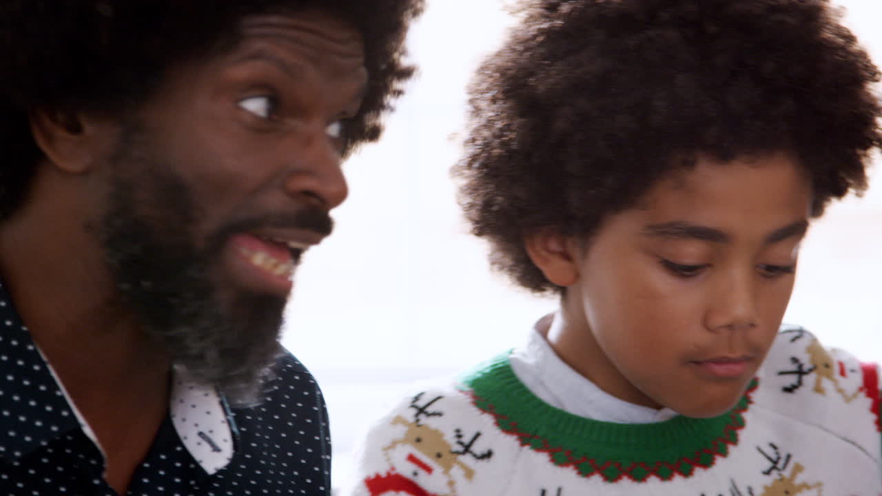 Panning shot of multi generation black family eating together sitting at the table on Christmas day, close up