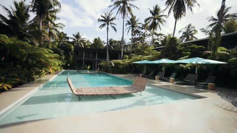 Empty-pool-at-luxurious,-calm-tropical-resort-with-pigeons-flying-by