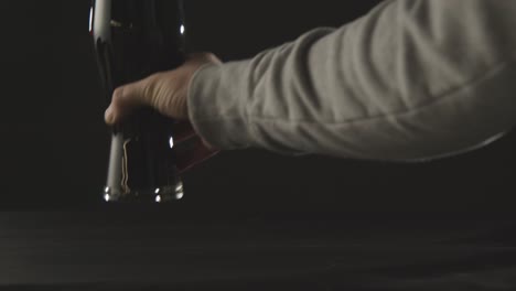 persona recogiendo una pinta de cerveza negra irlandesa en vidrio contra el fondo negro del estudio para celebrar el día 1 de san patricio