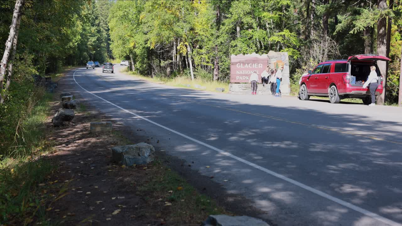 빙하 국립 공원, 몬타나 미국 - 2022년 9월 26일: 사진을 찍기 위해 빙하 국립 공원의 서쪽 입구에서 정차하는 차량과 관광객의 시간 경과