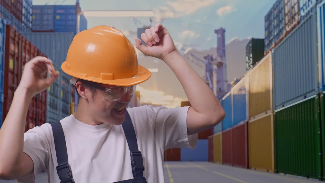primer plano de un trabajador asiático con gafas de protección y casco de seguridad bailando mientras está de pie en un almacén de contenedores