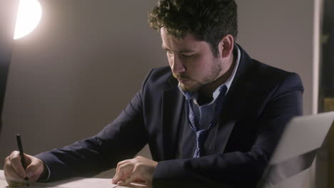 medium shot of young dark-haired man writing something