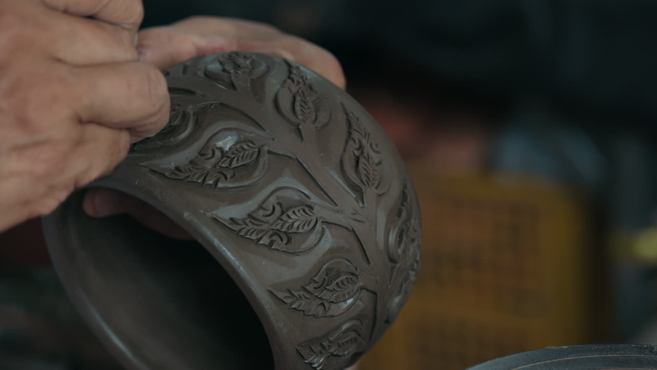 Hands crafting a decorative clay pot