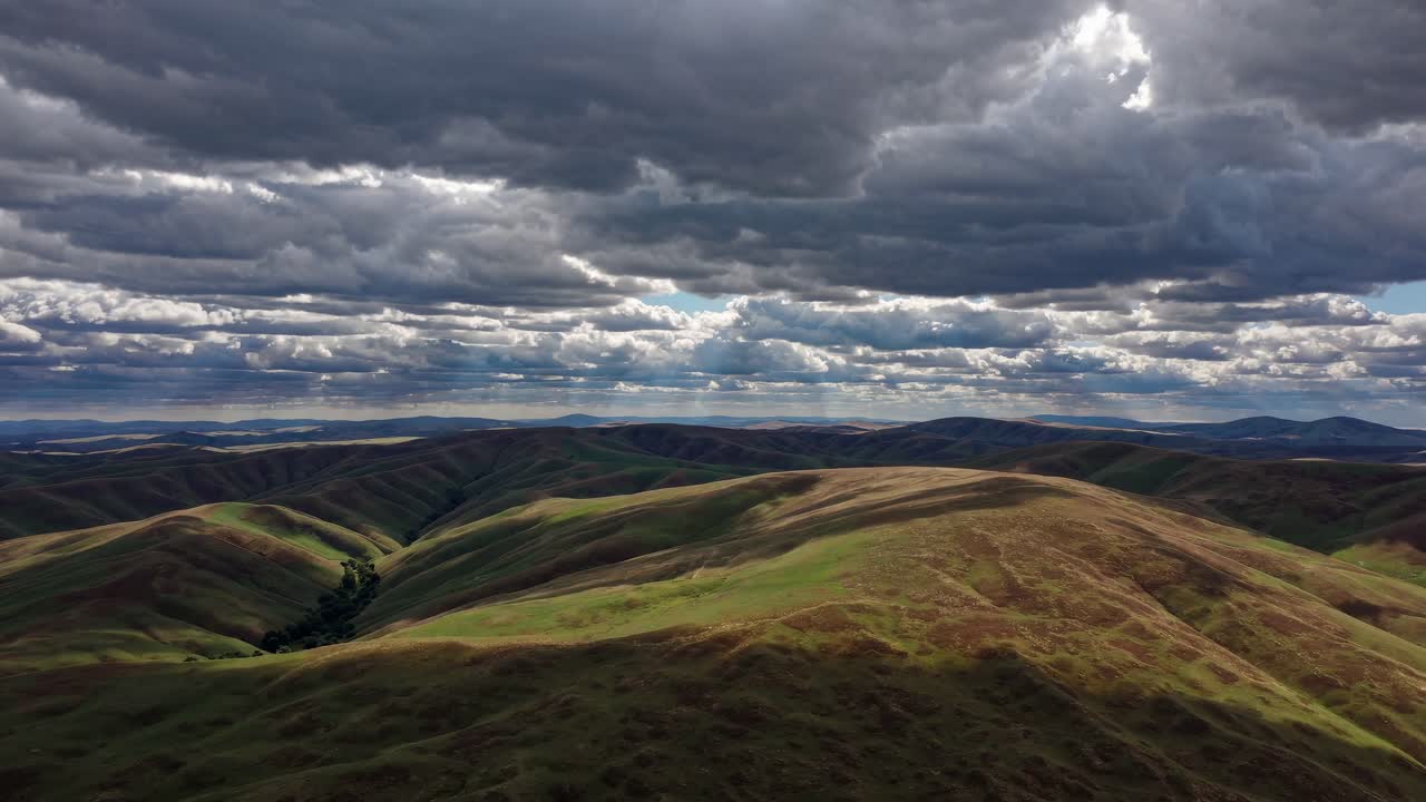 Aerial video view of rolling hills under dramatic cloudy skies