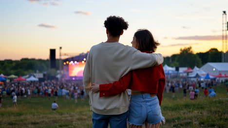 couple embracing and enjoying a music festival at sunset