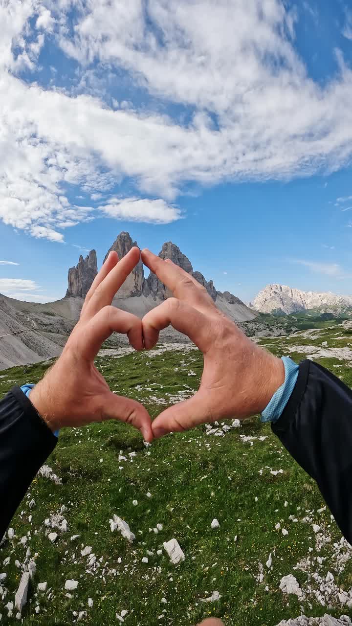 Hands shaped as heart express love for majestic Dolomite peaks and adventure