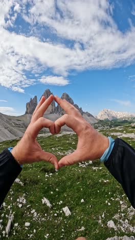 hands shaped as heart express love for majestic dolomite peaks and adventure